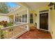 Inviting front porch with brick flooring, white railings, a dark wood front door, and well-maintained landscaping at 5902 Audubon Manor Blvd, Lithia, FL 33547