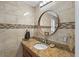 Stylish bathroom featuring a wood vanity, granite counters, and a round mirror at 6821 Date Palm S Ave, St Petersburg, FL 33707
