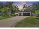 Charming single-story home featuring a long driveway, lush landscaping, and a two-car garage at sunset at 6821 Date Palm S Ave, St Petersburg, FL 33707