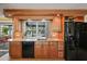 Functional kitchen featuring granite countertops, black appliances, wooden cabinets, and a view to the pool at 6821 Date Palm S Ave, St Petersburg, FL 33707