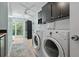 Bright laundry room with modern washer and dryer, storage cabinets, and access to the backyard at 6821 Date Palm S Ave, St Petersburg, FL 33707