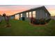View of the backyard with a lush lawn and minimal landscaping under a colorful sunset sky at 7323 Steer Blade Dr, Zephyrhills, FL 33541