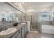 Bright bathroom with double sink vanity, granite countertops, and glass shower at 7323 Steer Blade Dr, Zephyrhills, FL 33541