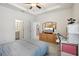 Bedroom with tray ceiling, dresser, and views into kitchen and bath at 7323 Steer Blade Dr, Zephyrhills, FL 33541