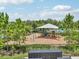 View of the playground with swings and slide, surrounded by trees, with a partial view of mailboxes at 7323 Steer Blade Dr, Zephyrhills, FL 33541