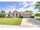 Inviting single-story home with a well-manicured lawn, arched windows, and a two-car garage at 7824 Primula Ln, New Port Richey, FL 34654