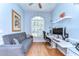 A bright and functional home office with hardwood floors, a modern desk, and a comfortable sofa at 7824 Primula Ln, New Port Richey, FL 34654