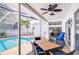 Enjoy outdoor dining under the ceiling fan with a pool view on the brick paver patio at 7824 Primula Ln, New Port Richey, FL 34654