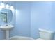 Simple powder room features a pedestal sink and a toilet, with light blue walls at 7824 Primula Ln, New Port Richey, FL 34654