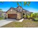 Inviting exterior with a two-car garage, arched entryway, fresh landscaping, and a well-manicured lawn at 8103 Tar Hollow Dr, Gibsonton, FL 33534