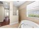 Bright bathroom with a tiled shower, garden tub under window, and doorway leading to another room at 8463 Dunham Station Dr, Tampa, FL 33647