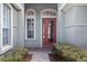 Close-up of a red front door with sidelights, enhanced by beautiful landscaping and lush greenery at 8463 Dunham Station Dr, Tampa, FL 33647