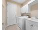 Bright laundry room with white cabinets, washer, dryer, and a utility sink for added convenience at 8463 Dunham Station Dr, Tampa, FL 33647