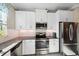 Well-lit kitchen features stainless steel appliances, granite countertops, and stylish white cabinets at 11548 Crowned Sparrow Ln, Tampa, FL 33626