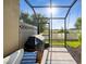Screened patio features outdoor grill and furniture with view of lawn at 11548 Crowned Sparrow Ln, Tampa, FL 33626