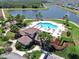 Aerial view of a community pool, clubhouse, and serene lake, offering residents a perfect place to relax and enjoy at 11625 Tetrafin Dr, Riverview, FL 33579