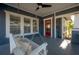 Charming front porch features a cozy swing, ceiling fan, and stylish red door for a warm welcome at 121 W Mohawk Ave, Tampa, FL 33604