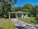 Charming single-story home with a carport, front porch with chairs, and well-maintained lawn on a sunny day at 131 Oak Park Ave, Brooksville, FL 34601