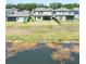 Expansive backyard view featuring a covered patio, lush green grass, and tranquil pond with natural surroundings at 14623 Horse Trot Rd, Lithia, FL 33547