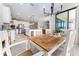 Bright dining area features wood table, white chairs, and a modern chandelier next to an open, airy kitchen at 14623 Horse Trot Rd, Lithia, FL 33547