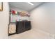 Functional laundry room with modern washer and dryer, shelving for storage, and a neutral color palette at 14623 Horse Trot Rd, Lithia, FL 33547