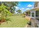 Spacious backyard with well-maintained lawn, bordered by lush greenery and a screened patio at 15034 Newport Rd, Clearwater, FL 33764