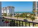 View from the balcony overlooking the street, beach, and palm trees with other buildings visible in the foreground at 1581 Gulf Blvd # 301N, Clearwater Beach, FL 33767
