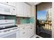 Bright kitchen features white cabinetry, stainless appliances, tile backsplash, and ocean view balcony at 1581 Gulf Blvd # 301N, Clearwater Beach, FL 33767