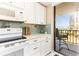 Cozy kitchen featuring white cabinets, light blue backsplash, and balcony access with views of the ocean at 1581 Gulf Blvd # 301N, Clearwater Beach, FL 33767