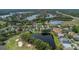 Aerial view of a community with homes surrounding a tranquil pond near a golf course at 18836 Maisons Dr, Lutz, FL 33558