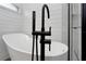 Modern bathroom with a freestanding tub, sleek black fixtures, and a walk-in shower at 18836 Maisons Dr, Lutz, FL 33558