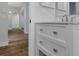 Close-up of a bathroom vanity with chrome fixtures and hardwood flooring in hallway at 18836 Maisons Dr, Lutz, FL 33558
