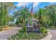 Entrance to the Cheval deed restricted community with lush tropical landscaping and an American flag at 18836 Maisons Dr, Lutz, FL 33558