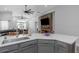 Open-concept kitchen with gray cabinets, quartz countertops, and view of living room with stone fireplace at 18836 Maisons Dr, Lutz, FL 33558