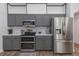 Modern kitchen featuring stainless steel appliances, gray cabinetry, quartz countertops, and tiled backsplash at 18836 Maisons Dr, Lutz, FL 33558