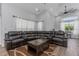 Bright living room with a large leather sectional sofa, coffee table, and large windows with sheer curtains at 18836 Maisons Dr, Lutz, FL 33558