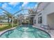 A screened pool has steps into the pool and is surrounded by lush landscaping at 18836 Maisons Dr, Lutz, FL 33558