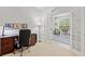 Bright home office features a dark wood desk and doorway with glass french doors at 19194 Lake Audubon Dr, Tampa, FL 33647
