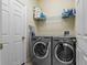 Practical laundry room with modern washer and dryer units and storage shelves at 20117 Indian Rosewood Dr, Tampa, FL 33647