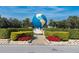 A large decorative globe centerpiece surrounded by manicured hedges and vibrant flowers at 2469 Franciscan Dr # 19, Clearwater, FL 33763