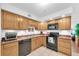Functional kitchen with natural wood cabinets, black appliances, and efficient use of space at 2469 Franciscan Dr # 19, Clearwater, FL 33763