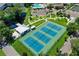 Aerial view of community tennis courts, with a pond, clubhouse, and pool in the background at 2469 Franciscan Dr # 19, Clearwater, FL 33763