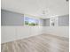 Neutral room with wood-look flooring, two windows, and white wainscoting at 2616 Ohio Pl, Holiday, FL 34691