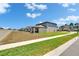 Spacious backyard showcasing the home's exterior, with a walkway, lawn, and a fence at 34780 Rainville Loop, Zephyrhills, FL 33541