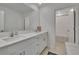 Bathroom with double sinks, white cabinets, shower, and wood-look tile flooring at 34780 Rainville Loop, Zephyrhills, FL 33541