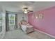 Cozy bedroom with bright pink accent wall, ceiling fan and plush decor, illuminated by a large window at 34780 Rainville Loop, Zephyrhills, FL 33541