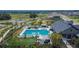 An aerial view showcases the community pool with its lounge area, lush greenery, and modern clubhouse at 34780 Rainville Loop, Zephyrhills, FL 33541