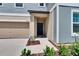 Charming home featuring a welcoming front door with beige siding and an attached garage, with landscaped front yard at 34780 Rainville Loop, Zephyrhills, FL 33541