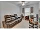 Inviting living room showcasing a plush black leather sofa, a ceiling fan, and a well-lit desk setup at 34780 Rainville Loop, Zephyrhills, FL 33541