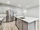 Modern kitchen with gray cabinets, stainless steel appliances, quartz countertops, and wood-style tile flooring at 3764 Laughing Dove Ave, Sun City Center, FL 33573